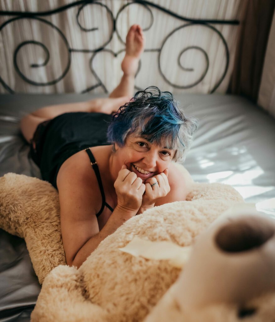 Tracy Lee lying on the bed with a teddy