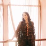 Dakini Aurora Rose in a black dress in front of a window