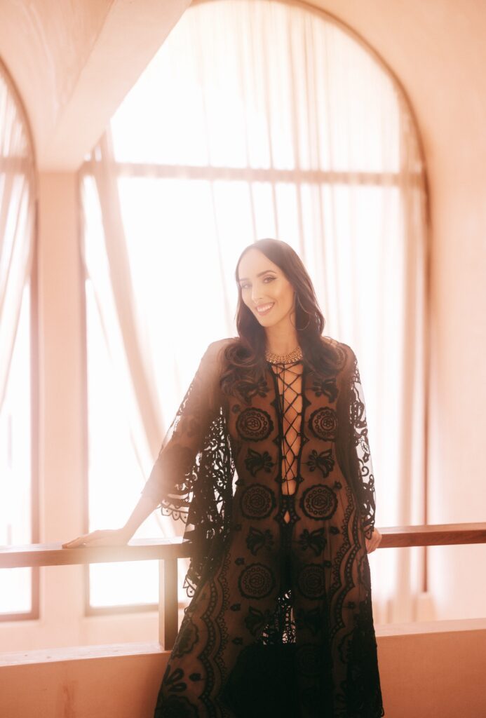Dakini Aurora Rose in a black dress in front of a window
