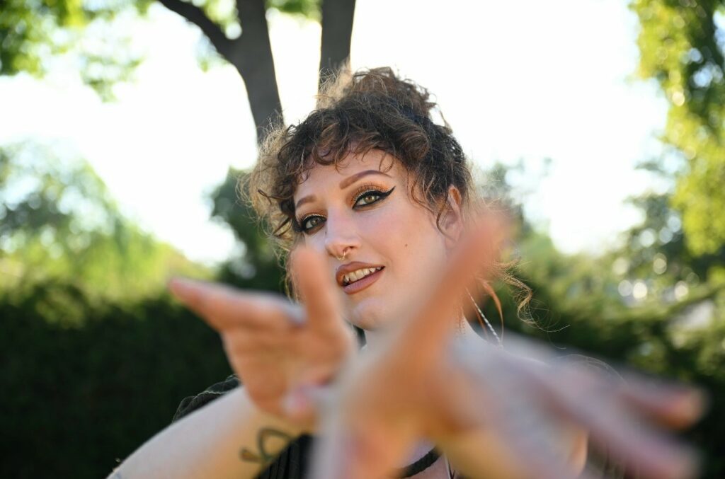 Nickie Jean out in nature gesturing towards the camers