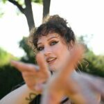 Nickie Jean out in nature gesturing towards the camers