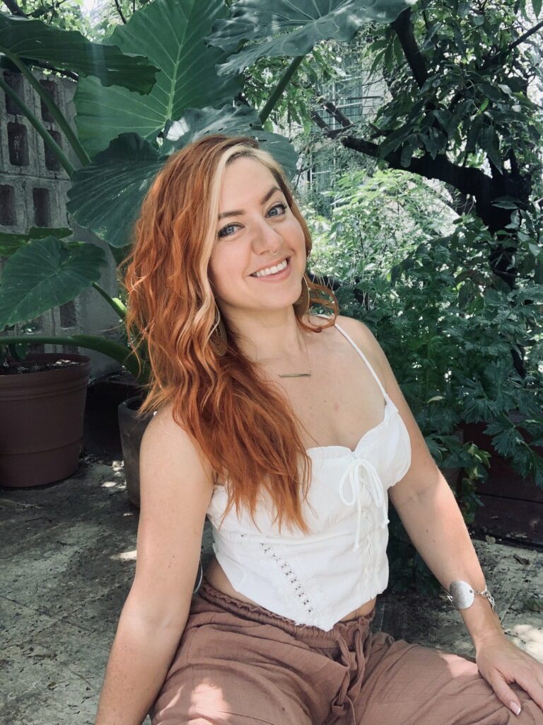 Sureya sitting in a white shirt and smiling