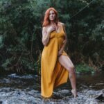 Inanna standing in a yellow dress in nature