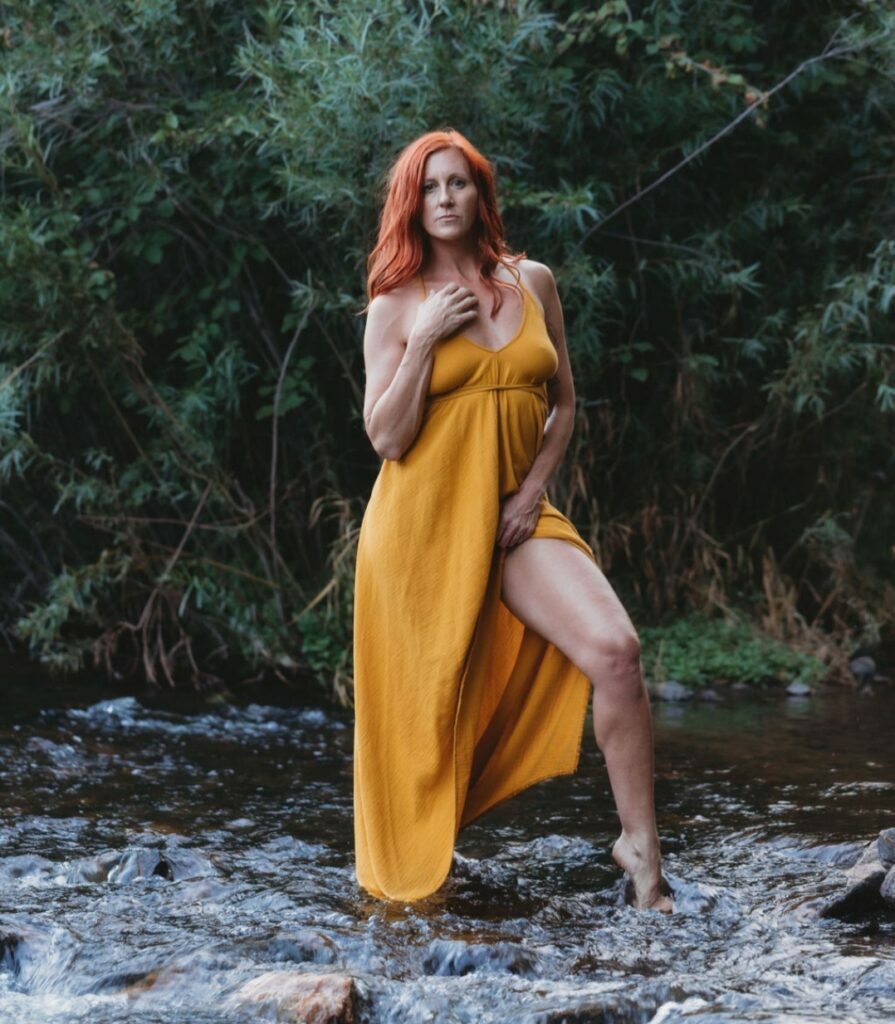 Inanna standing in a yellow dress in nature