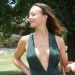 Olivia wearing a green dress that exposes the tattoo "Love" on her chest.