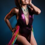 Angela in a purple shiny dress and rainbow-colored scarf.