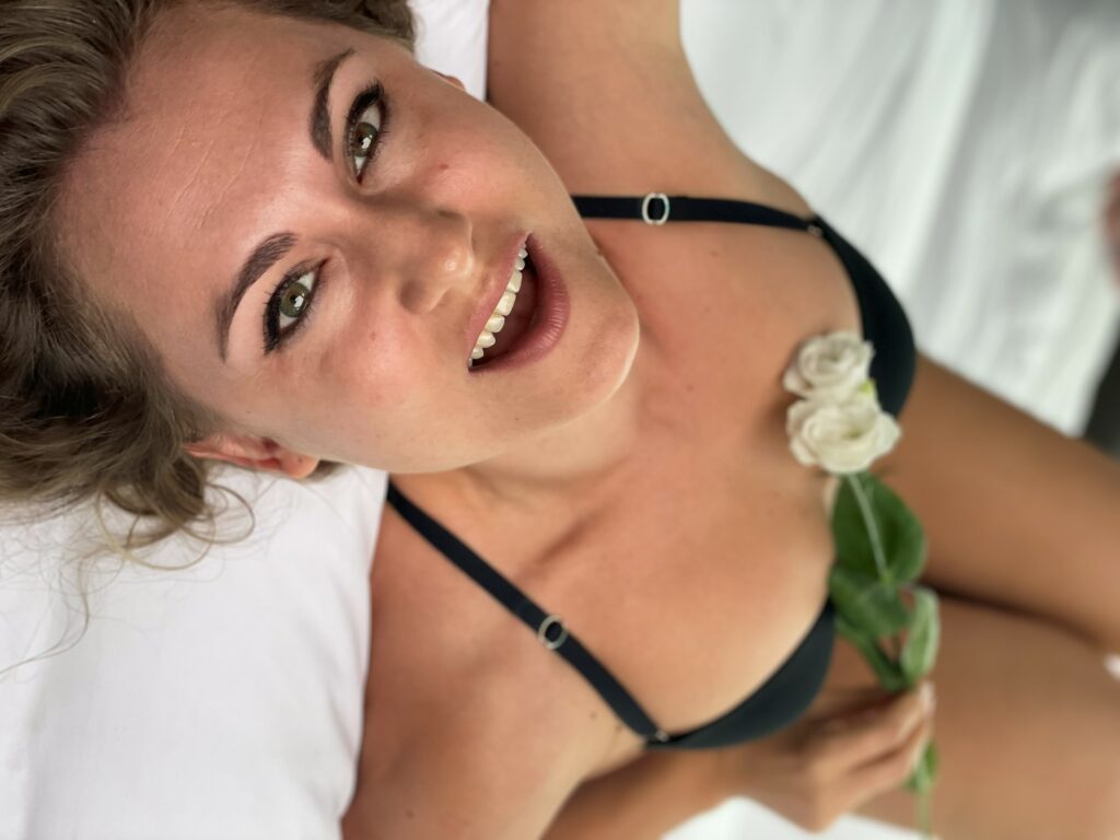 Dakini Gaya on the bed in lingerie. White flower on her breast