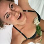 Dakini Gaya on the bed in lingerie. White flower on her breast