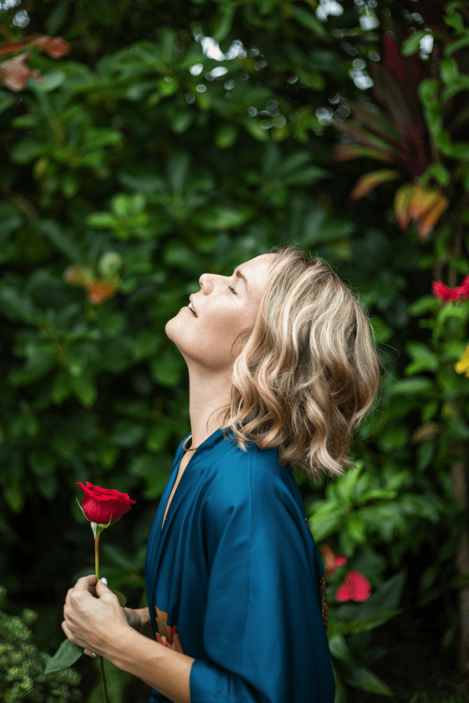 Venus Rose ina blue dressing looking up and holding a rose