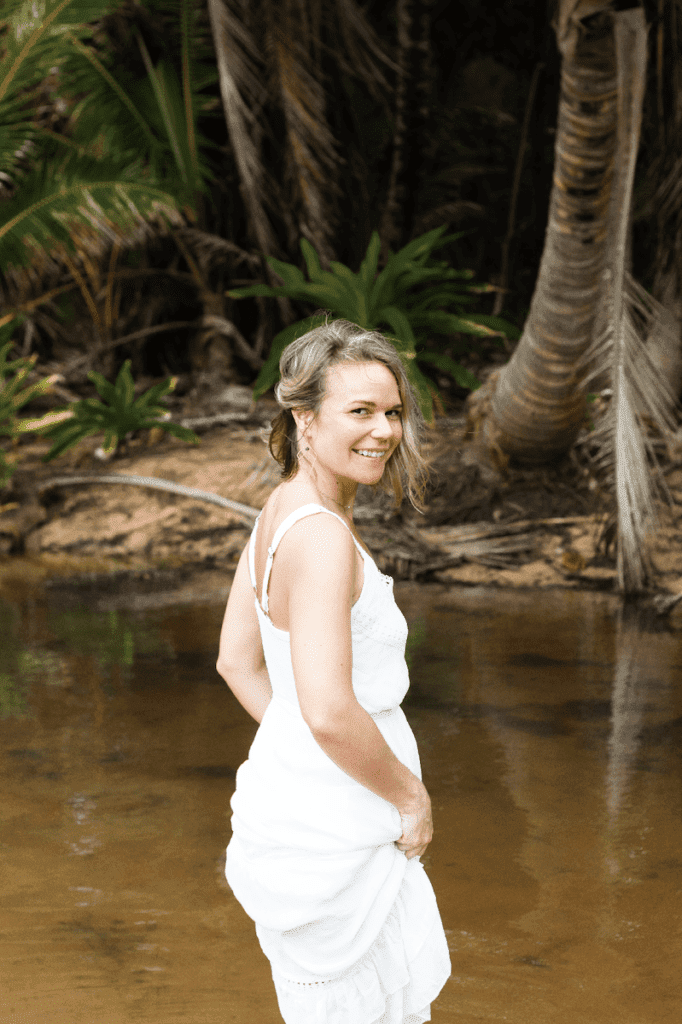 Rose walking thorugh water holding up her white dress