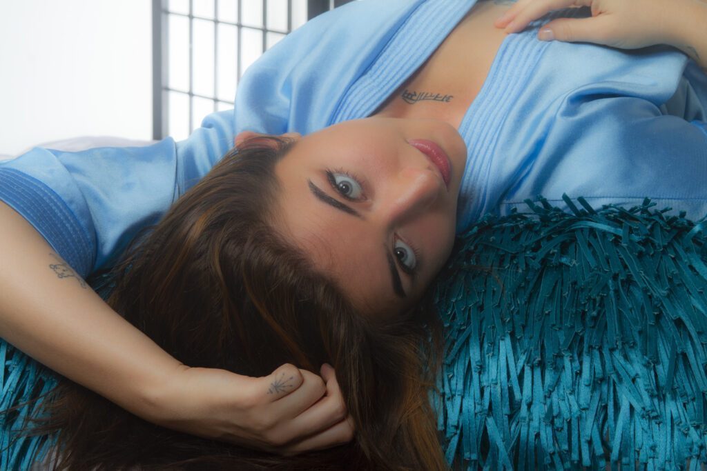 Sensual shot of Syra lying down in a silk dress.
