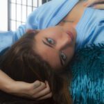 Sensual shot of Syra lying down in a silk dress.