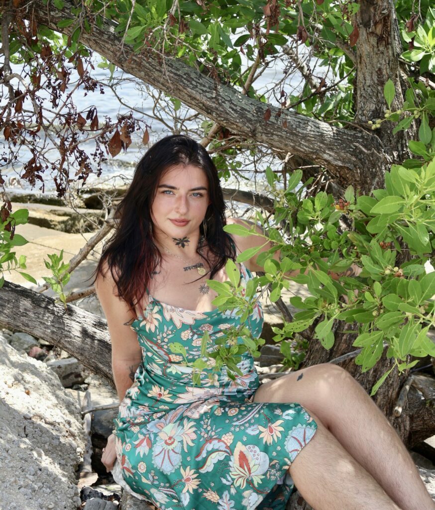 Syra sitting on the rocks in a colorful patterned dress.