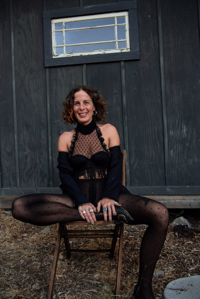 Sitting on a chair and smiling wide.