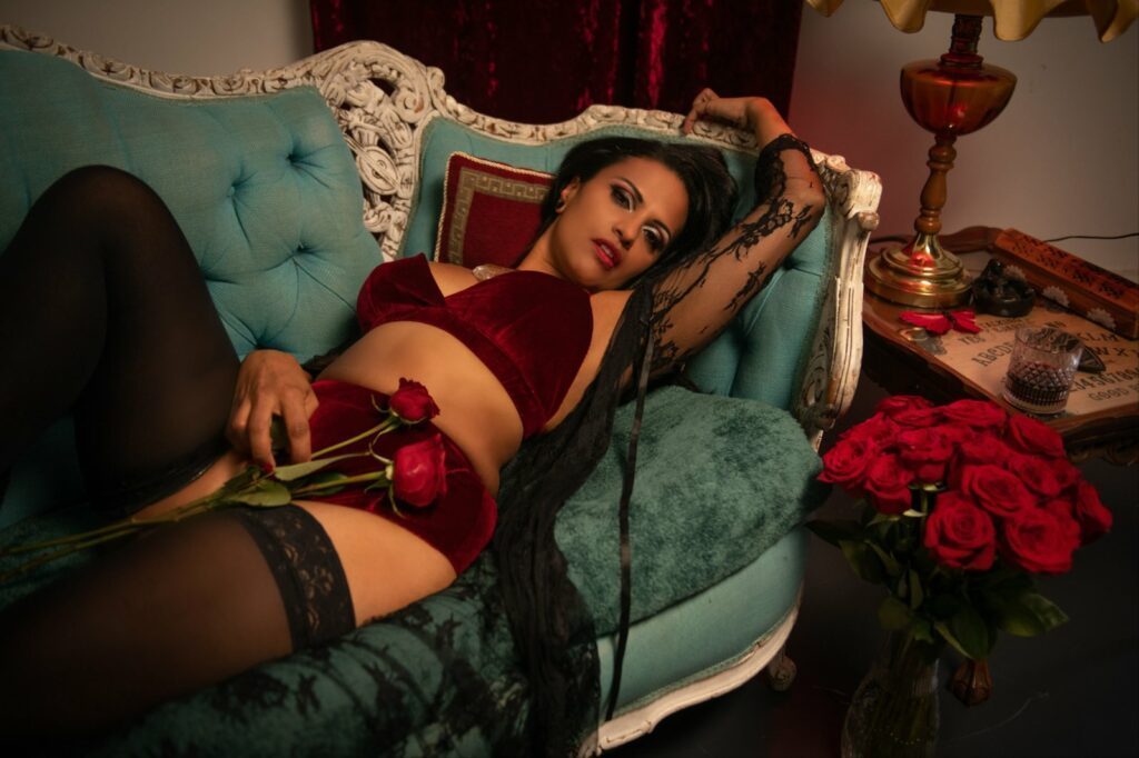Sensual shot of Lilith Noir on the sofa wearing red velvety underwear.