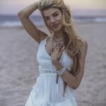 Sitting on the beach in a white dress.