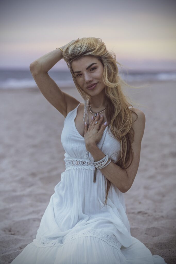 Sitting on the beach in a white dress.