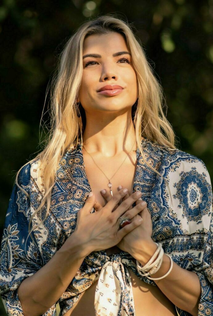 Sun shining on Dahlia's face. She has her hands crossed in front of her chest.