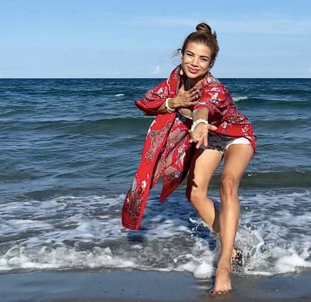 Standing in the sea reaching her hand out towards the camera.