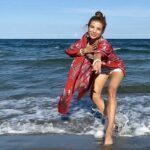 Standing in the sea reaching her hand out towards the camera.