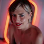 Mistress Em with a glowing orange mirror behind her