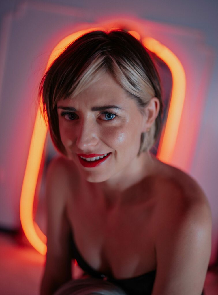 Mistress Em with a glowing orange mirror behind her