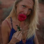 Aurora Love smelling a red rose