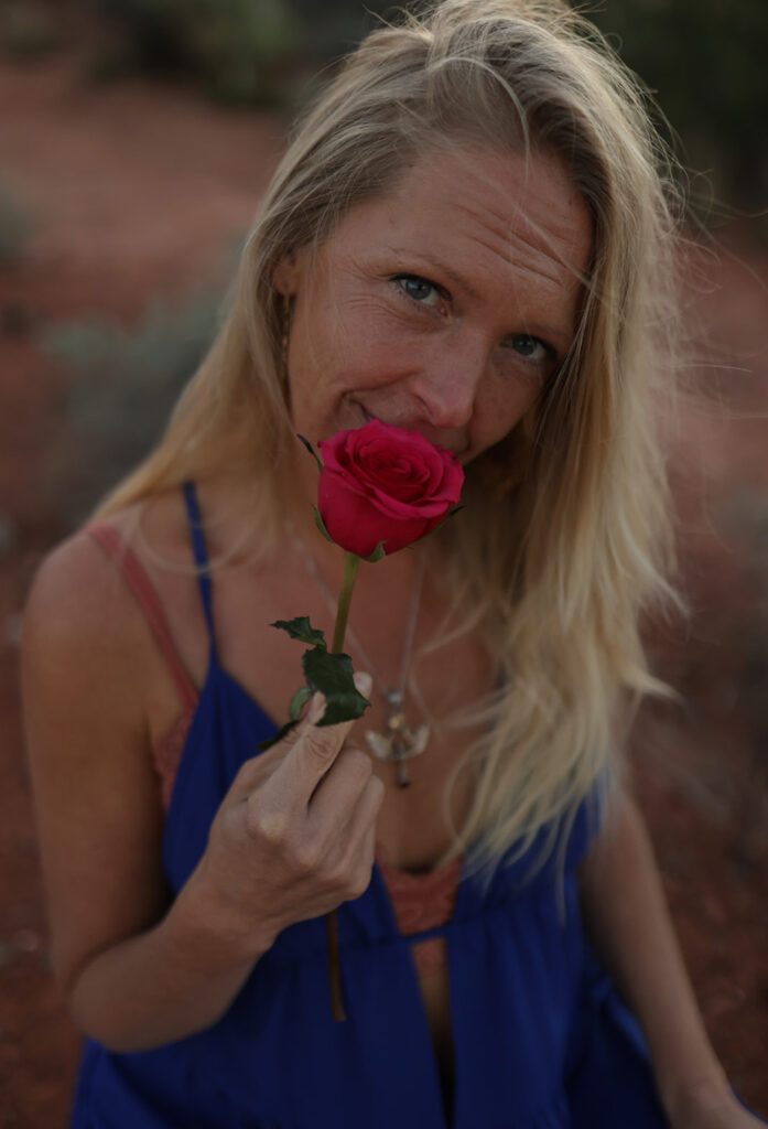 Aurora Love smelling a red rose