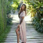 Amy in a long beautiful pink dress standing in an alley of trees.