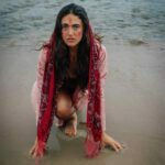 Anna Ruth squatting on the beach in water with red paint on her face.