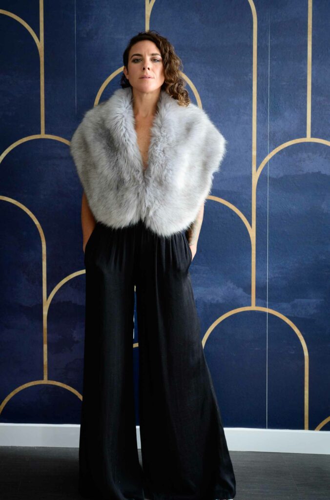 Lila wearing a fluffy coat and black trousers.