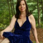 Ella Rose in a blue dress surrounded by trees