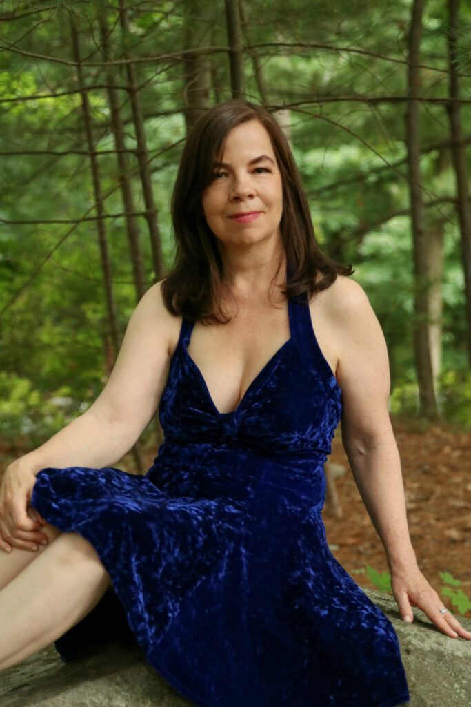 Ella Rose in a blue dress surrounded by trees