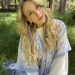 Blonde hair, white jacket, Kora is tilting her head and looking to the camera.