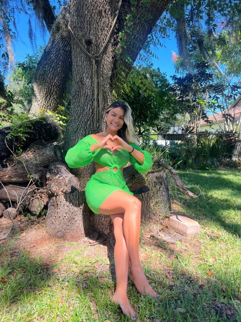 Ellie f dressed in green sitting in front of a tree