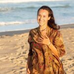 Standing Moriah with the sea holding her hand over her heart.