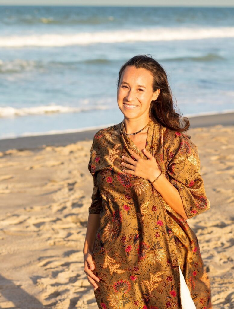 Standing Moriah with the sea holding her hand over her heart.