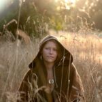 Priestess Hannah hooded in tall grass