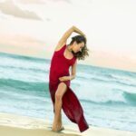 Moriah in a red dress on the beach.