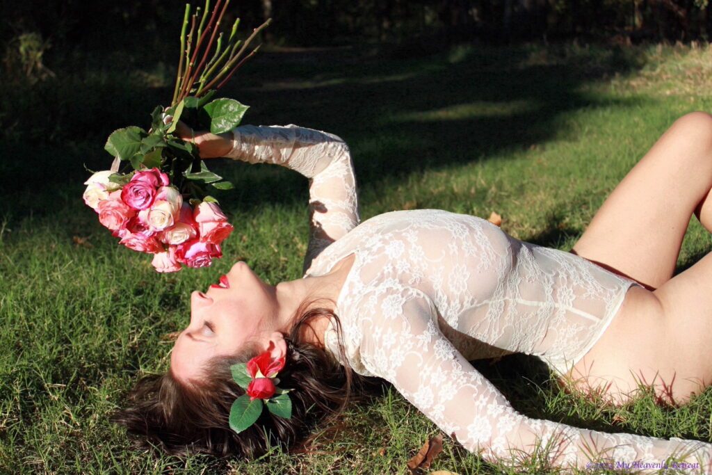 Sensual shot of Nohemi on the grass holding a buquet of roses.