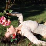 Sensual shot of Nohemi on the grass holding a buquet of roses.