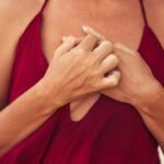 Close up of a chest in red shirt. Her hands are crossed in front of the chest.