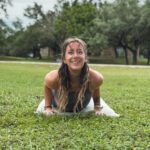 Natalie doing an upward dog like yoga pose on the grass.