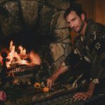 Sebastian laying flowers in front of a fire