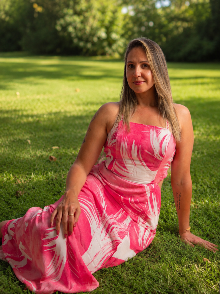 Andrea sitting on the grass in a pink dress