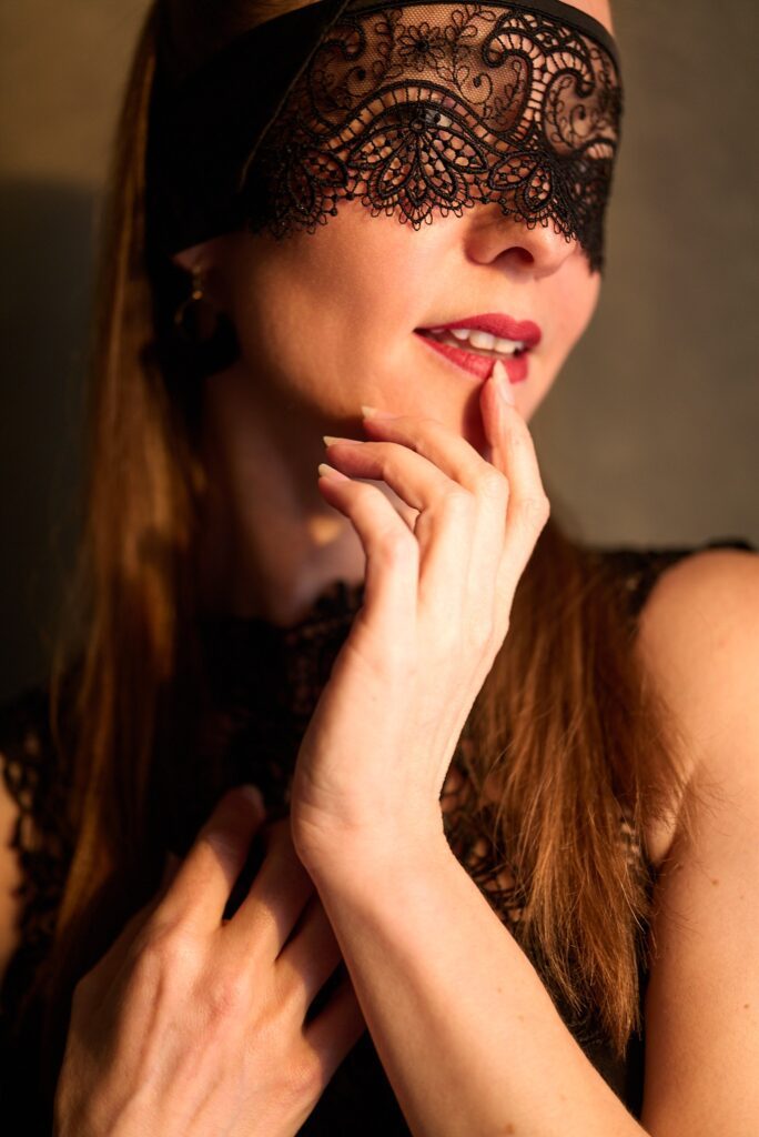Enticing Elaine holding her finger near her mouth and wearing a mask.
