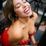 Mayra in a red dress that exposes her shoulders.