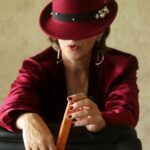 Madame Jae in a red jacket and a hat.