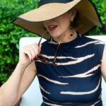 Madame Jae wearing a big straw hat covering half of her face.
