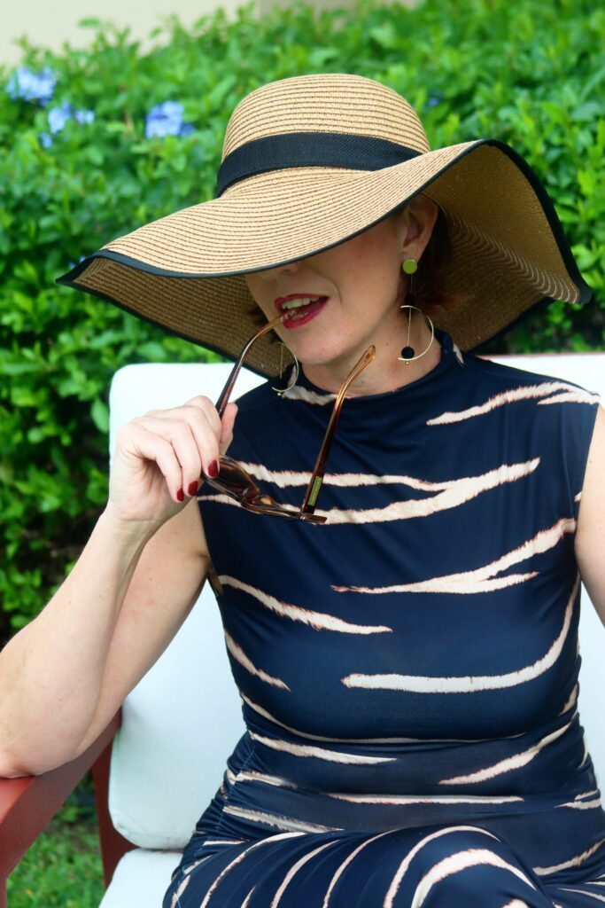 Madame Jae wearing a big straw hat covering half of her face.